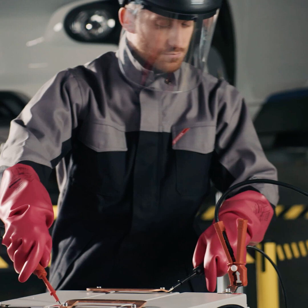 Video thumbnail on the topic of work safety: Close-up of a person wearing robust, red and black protective gloves.